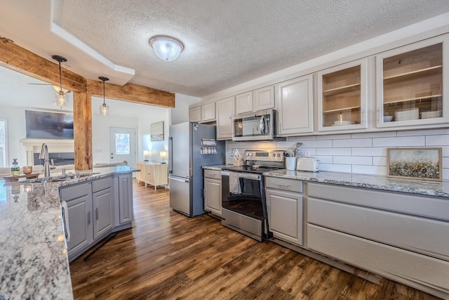 kitchen with sink, decorative backsplash, hanging light fixtures, light stone counters, and stainless steel appliances