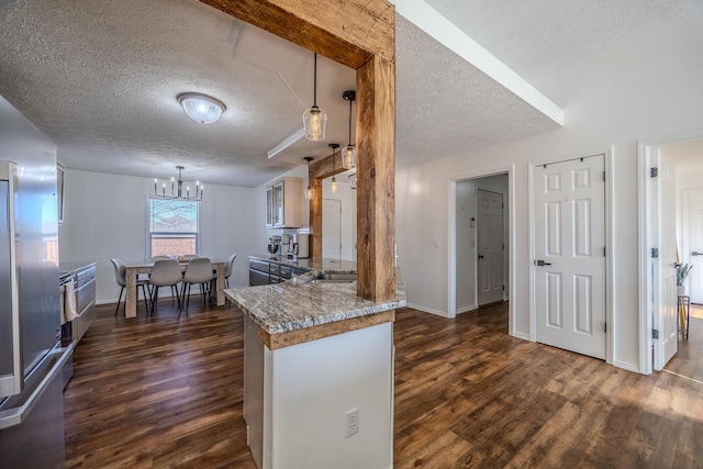 kitchen featuring pendant lighting, dark hardwood / wood-style flooring, light stone countertops, and a chandelier