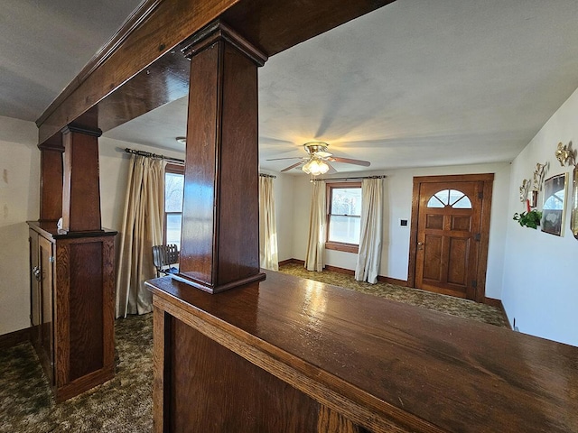 carpeted entrance foyer with decorative columns and ceiling fan