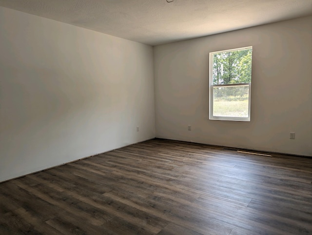 spare room featuring dark hardwood / wood-style floors and a textured ceiling