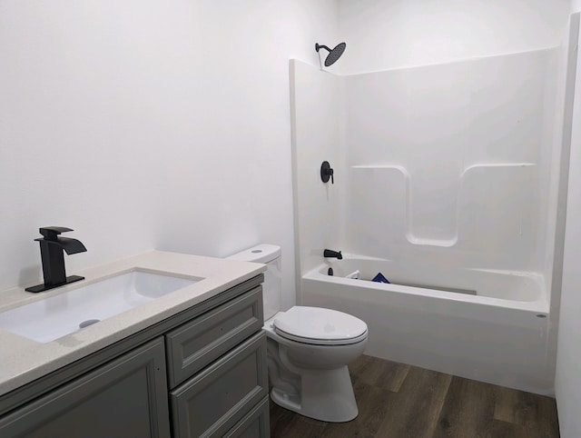 full bathroom featuring hardwood / wood-style flooring, washtub / shower combination, vanity, and toilet