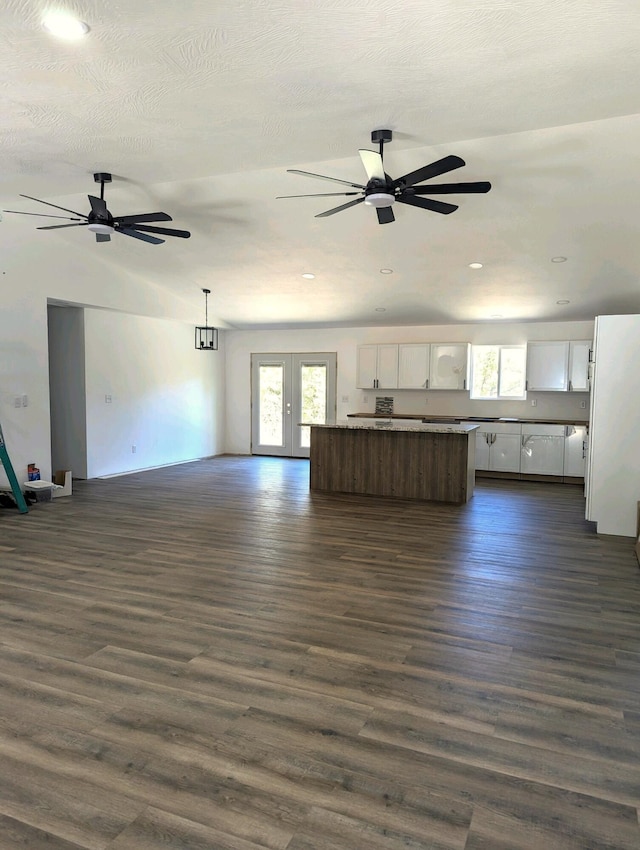 unfurnished living room featuring dark hardwood / wood-style flooring, lofted ceiling, french doors, and ceiling fan