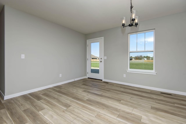 unfurnished dining area with light wood-type flooring and a chandelier