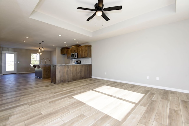 kitchen featuring a raised ceiling, light hardwood / wood-style floors, and decorative light fixtures