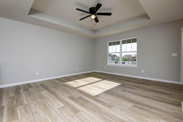 spare room featuring a tray ceiling, light hardwood / wood-style flooring, and ceiling fan