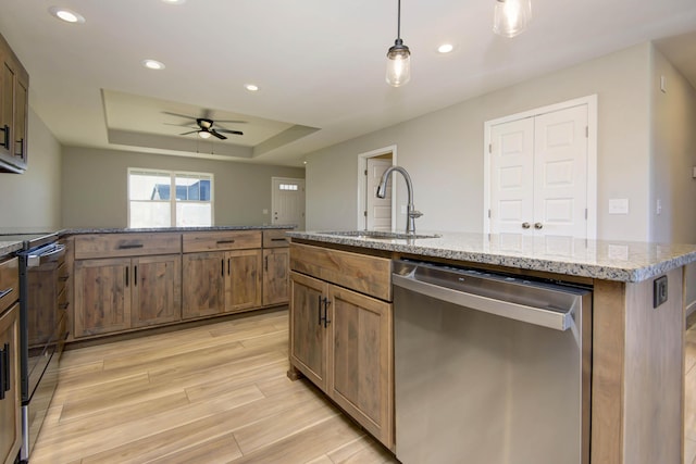 kitchen with sink, hanging light fixtures, a center island with sink, stainless steel dishwasher, and a raised ceiling