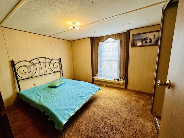 carpeted bedroom featuring a textured ceiling and wooden walls