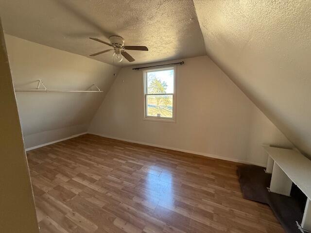 bonus room featuring hardwood / wood-style flooring, lofted ceiling, and a textured ceiling