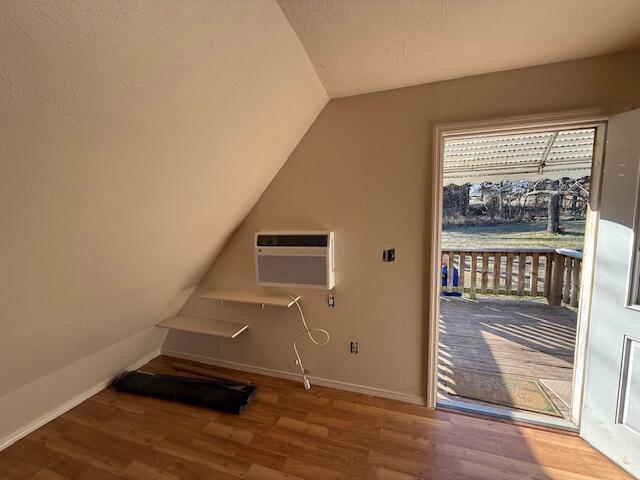 washroom featuring hardwood / wood-style flooring, a wall mounted AC, and a textured ceiling