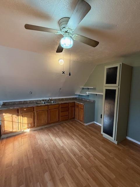 kitchen with sink, light hardwood / wood-style flooring, a textured ceiling, and ceiling fan