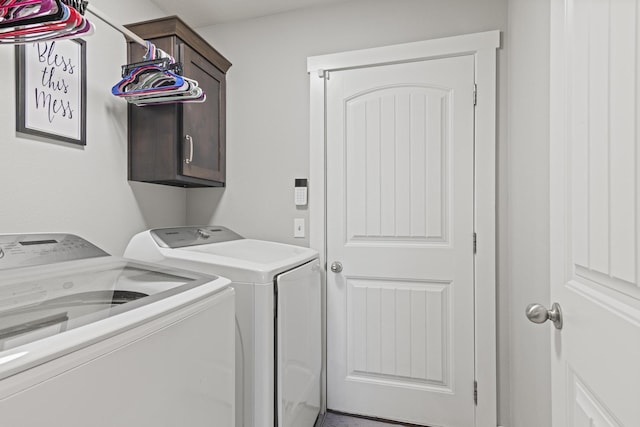 clothes washing area featuring separate washer and dryer and cabinets