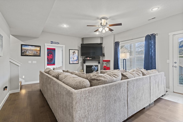 living room featuring dark wood-type flooring, a textured ceiling, and ceiling fan