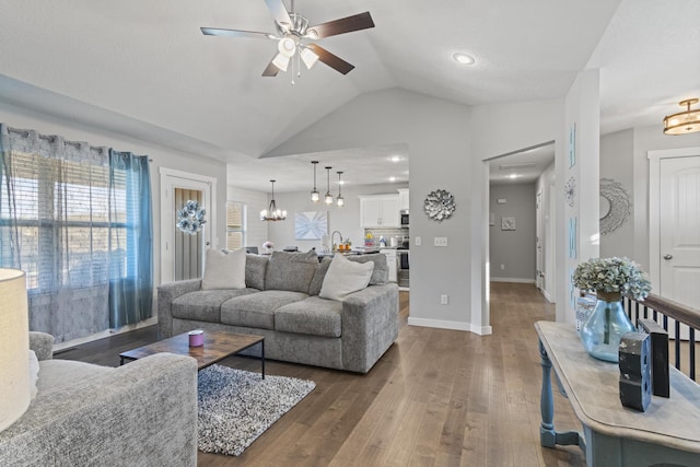 living room featuring lofted ceiling, ceiling fan with notable chandelier, and dark hardwood / wood-style flooring