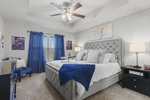 bedroom with a raised ceiling, carpet floors, and ceiling fan