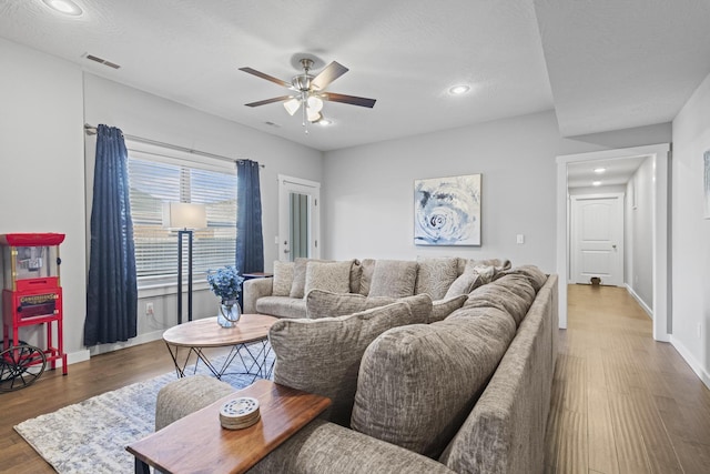 living room with a textured ceiling, dark hardwood / wood-style floors, and ceiling fan