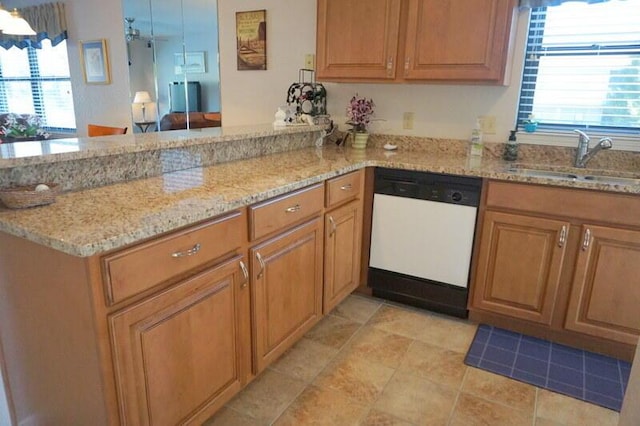 kitchen featuring white dishwasher, kitchen peninsula, light stone countertops, and a wealth of natural light