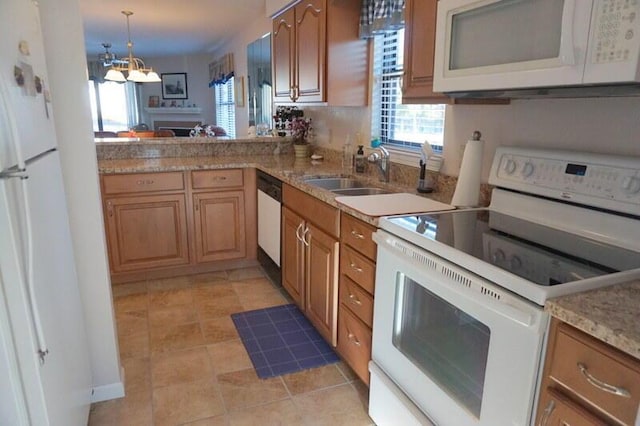 kitchen featuring sink, white appliances, hanging light fixtures, kitchen peninsula, and a chandelier