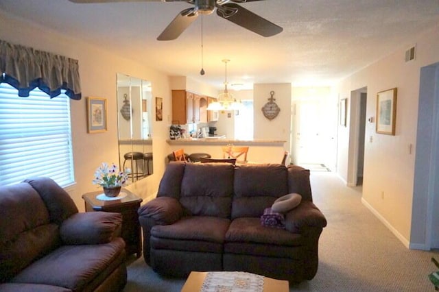 living room featuring a healthy amount of sunlight, ceiling fan with notable chandelier, and light carpet