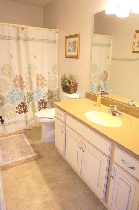 bathroom with walk in shower, vanity, and toilet