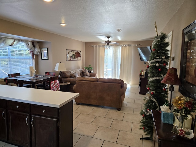 tiled living room with ceiling fan, a textured ceiling, and a healthy amount of sunlight