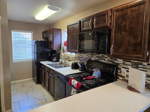 kitchen with sink, backsplash, light tile patterned floors, dark brown cabinetry, and black appliances