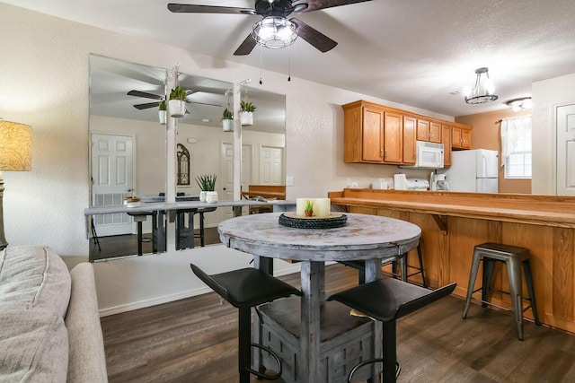 kitchen featuring ceiling fan, dark wood-type flooring, pendant lighting, and white appliances