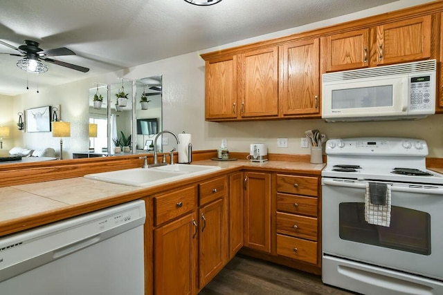 kitchen with sink, ceiling fan, tile counters, dark hardwood / wood-style flooring, and white appliances