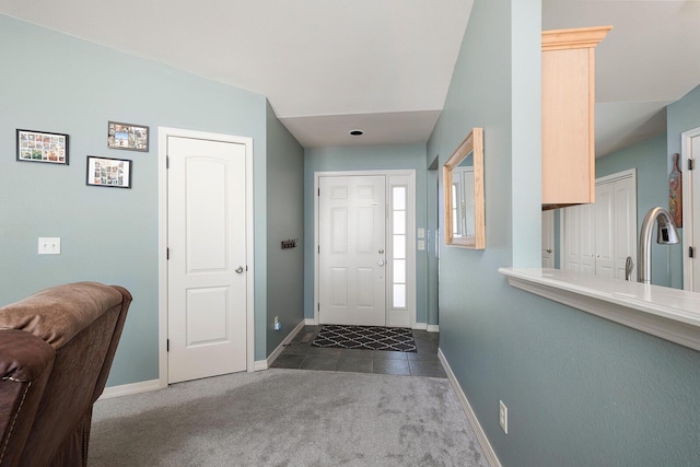 entrance foyer with sink and dark colored carpet