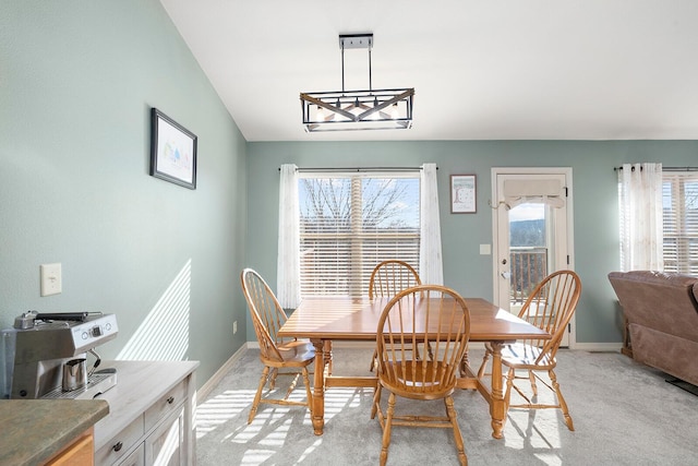 dining room with lofted ceiling, a healthy amount of sunlight, and light carpet