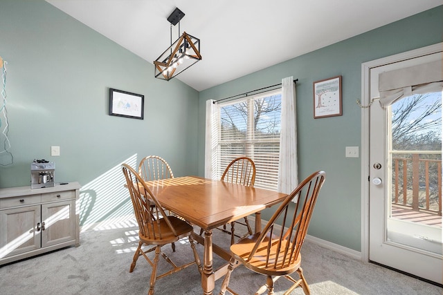 carpeted dining room featuring vaulted ceiling