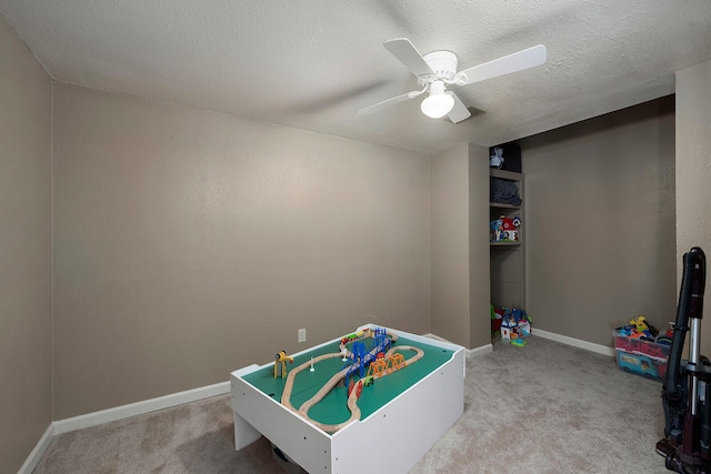 playroom with ceiling fan, carpet, and a textured ceiling