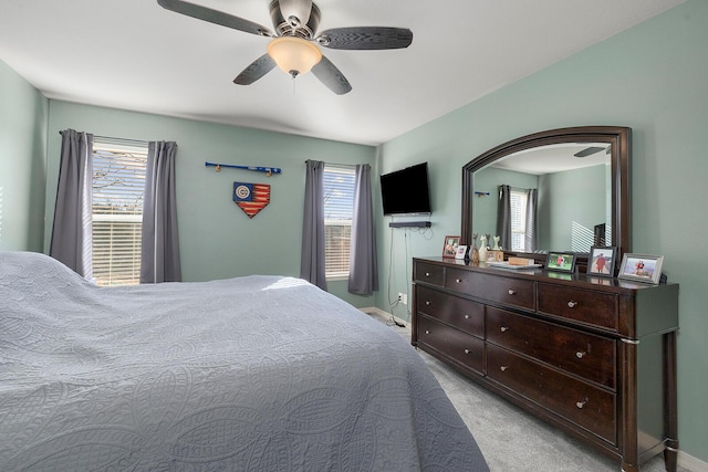 carpeted bedroom featuring multiple windows and ceiling fan