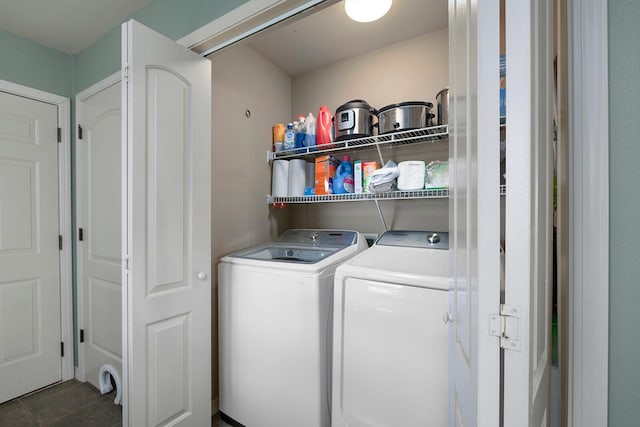 clothes washing area featuring dark tile patterned flooring and washer and dryer