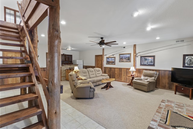 living room featuring vaulted ceiling, light carpet, ceiling fan, and wood walls