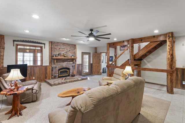 living room featuring ceiling fan, a fireplace, and wood walls