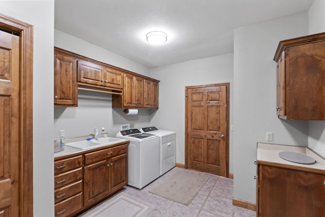 laundry area with cabinets, washing machine and clothes dryer, light tile patterned flooring, and sink