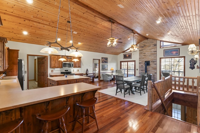 kitchen featuring appliances with stainless steel finishes, beam ceiling, decorative light fixtures, and high vaulted ceiling