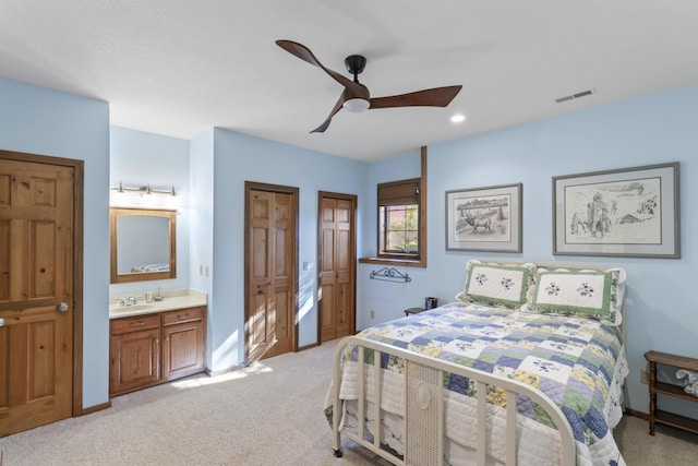 carpeted bedroom with ceiling fan, connected bathroom, and sink