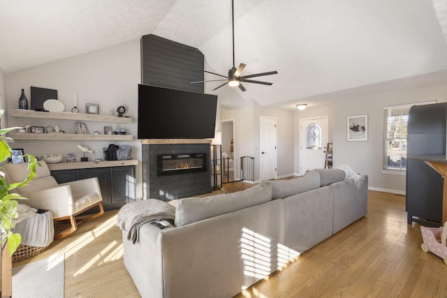 living room featuring ceiling fan, lofted ceiling, and light hardwood / wood-style floors