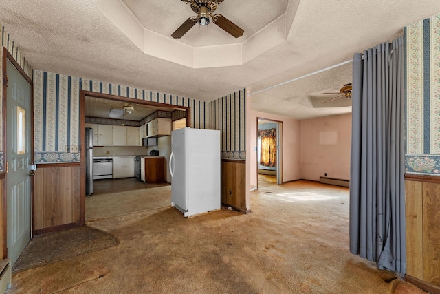 interior space featuring ceiling fan, a baseboard heating unit, a textured ceiling, light colored carpet, and wood walls