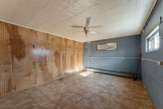 spare room with ceiling fan, wood walls, a wall unit AC, and a baseboard heating unit