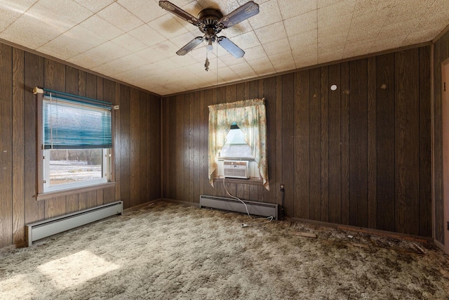 carpeted empty room featuring baseboard heating, ceiling fan, and wood walls