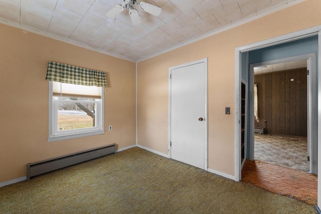 unfurnished bedroom with crown molding, wooden walls, carpet floors, ceiling fan, and a baseboard heating unit