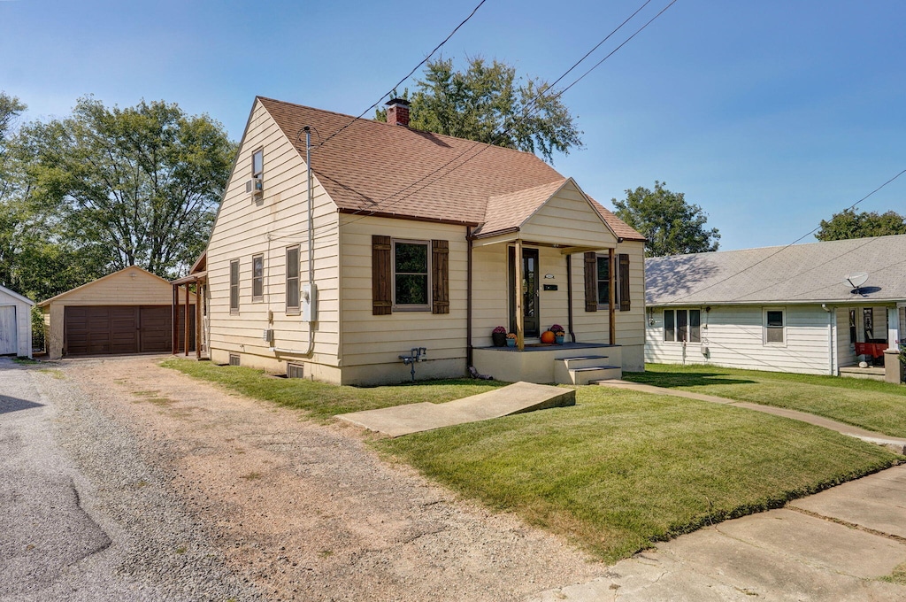 bungalow-style home with a garage, an outbuilding, and a front lawn