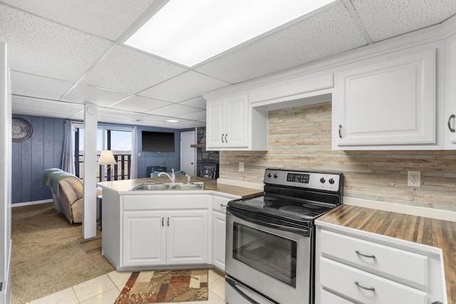 kitchen with white cabinets, stainless steel range with electric stovetop, kitchen peninsula, and a drop ceiling