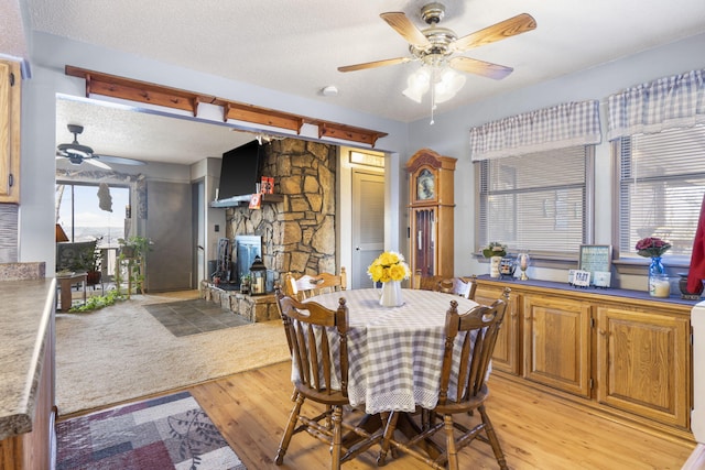 dining space with ceiling fan, a textured ceiling, and light wood-type flooring