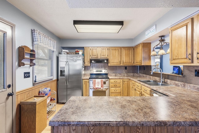 kitchen featuring sink, a textured ceiling, wooden walls, stainless steel appliances, and backsplash