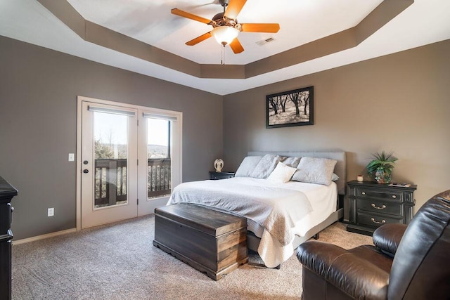 carpeted bedroom with ceiling fan, a raised ceiling, and access to outside