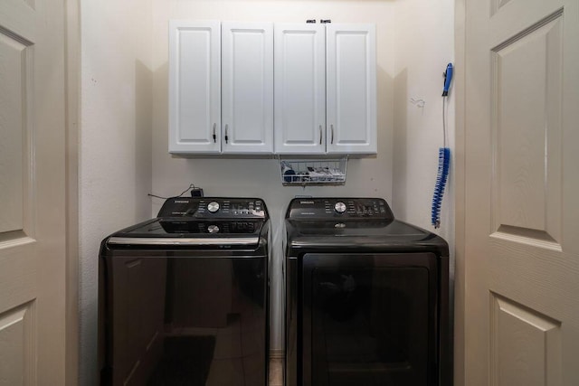 clothes washing area featuring cabinets and washer and clothes dryer