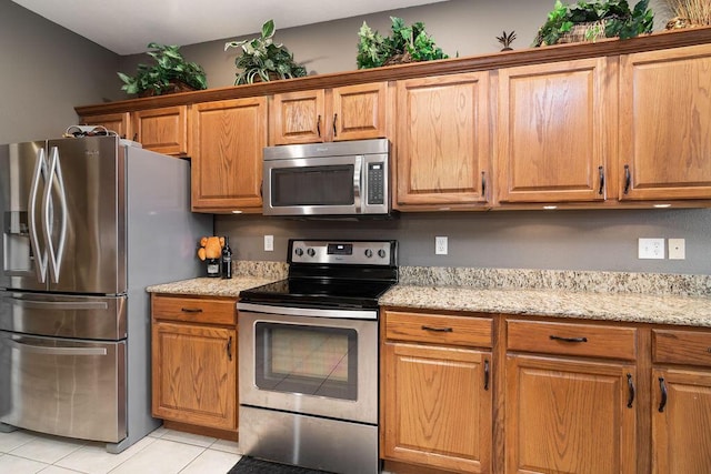 kitchen with light stone counters, appliances with stainless steel finishes, and light tile patterned floors